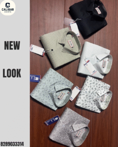 Folded printed and textured shirts in various colors arranged neatly on a wooden surface, showcasing a stylish new collection.