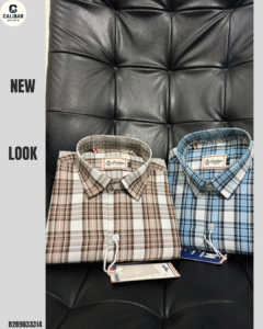 A brown and a blue checkered shirt, both folded, are displayed on a black leather chair. The shirts have brand tags attached. The brown shirt is on the left, and the blue shirt is on the right.