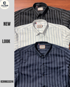 Three neatly folded striped men’s formal shirts in black, white, and navy blue placed on a wooden surface – Calibar brand.