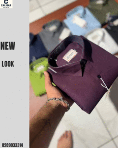 Maroon Calibar shirt being held, with multiple shirt colors in the background.